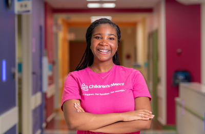 Female nurse in hot pink shirt with arms crossed. 