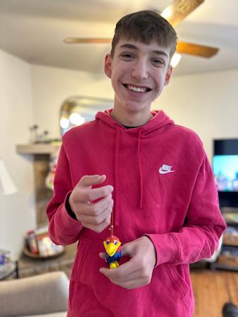 Young person wearing a red hoodie and holding a keychain with a bird