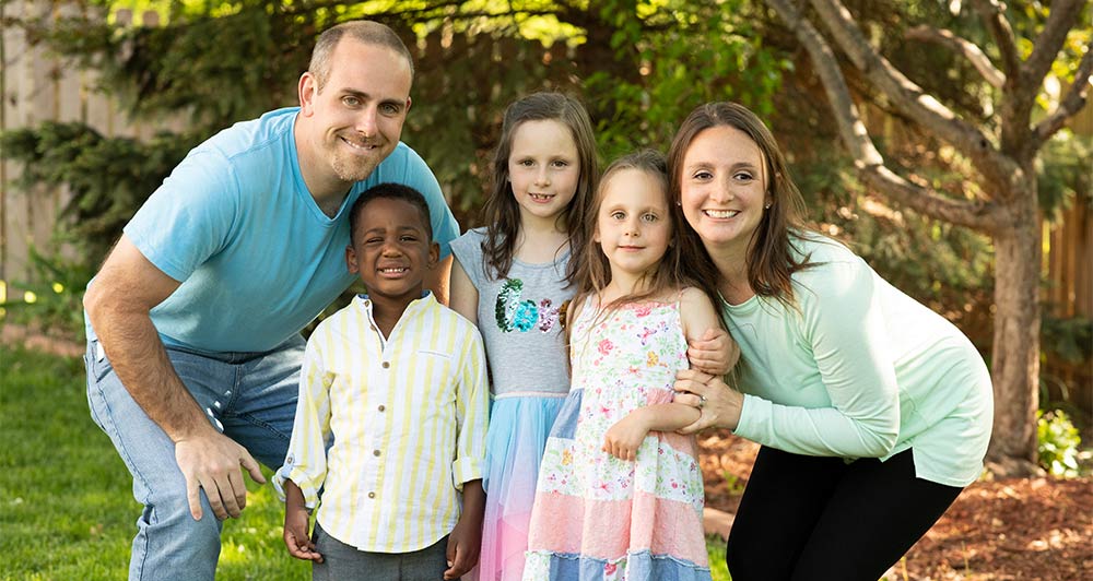 two parents, three kids pose outside for a family photos