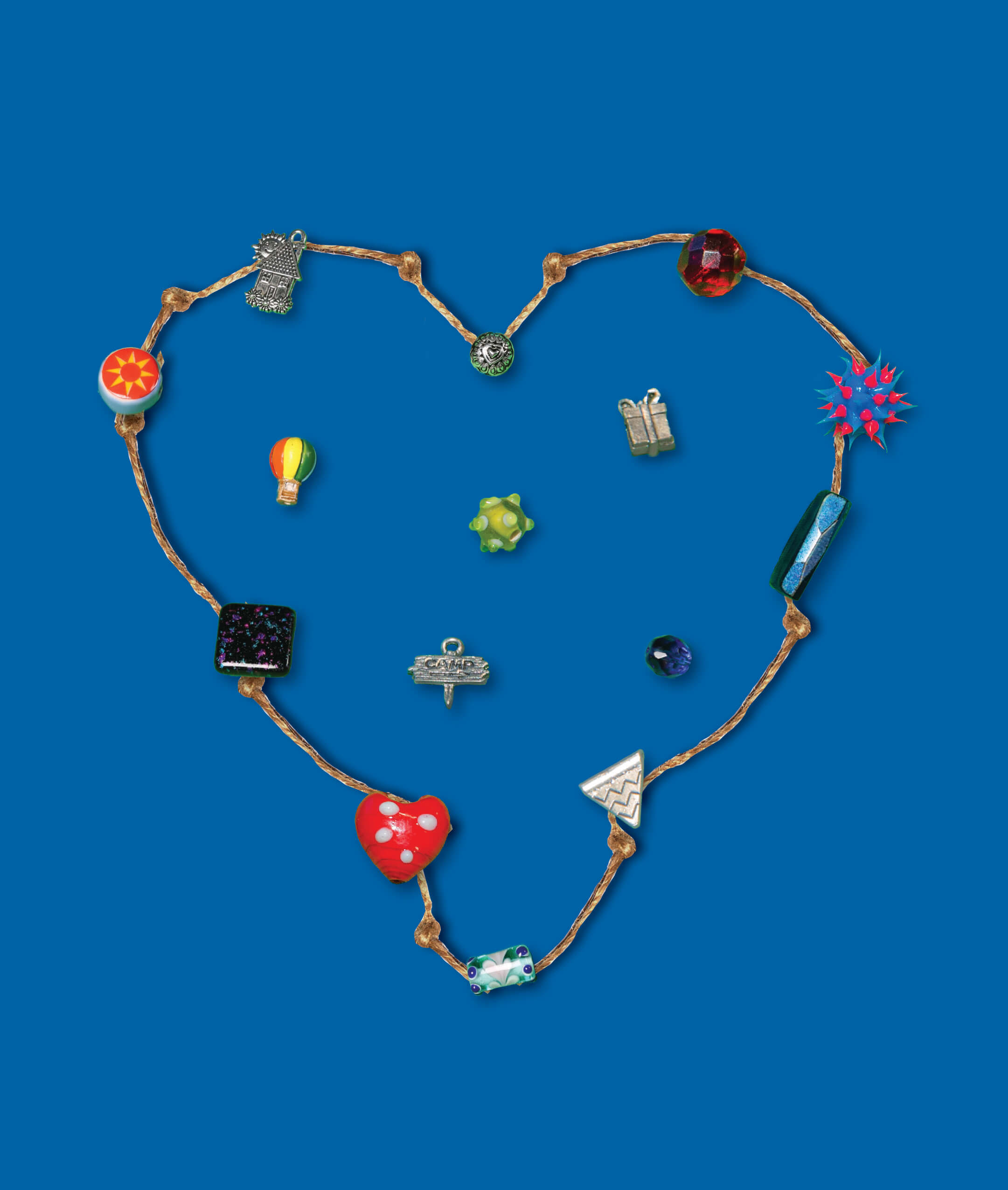 Heart-shaped bracelet made of twine and colorful beads, charms and decorative accents displayed against a blue background.