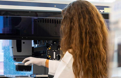 Close-up of a laboratory professional loading samples into automated testing equipment in a clinical laboratory