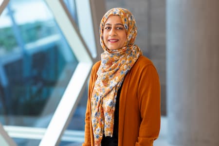 Children's Mercy employee in orange cardigan and flower printed Hijab smiling. 