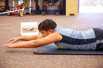 photo of young patient lying on their stomach on the floor working through spin and back exercises