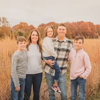 image of a family of five posing for a family picture in a field