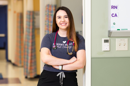 Children's Mercy nurse posing with crossed arms and smiling while leaning against a wall in clinic. 