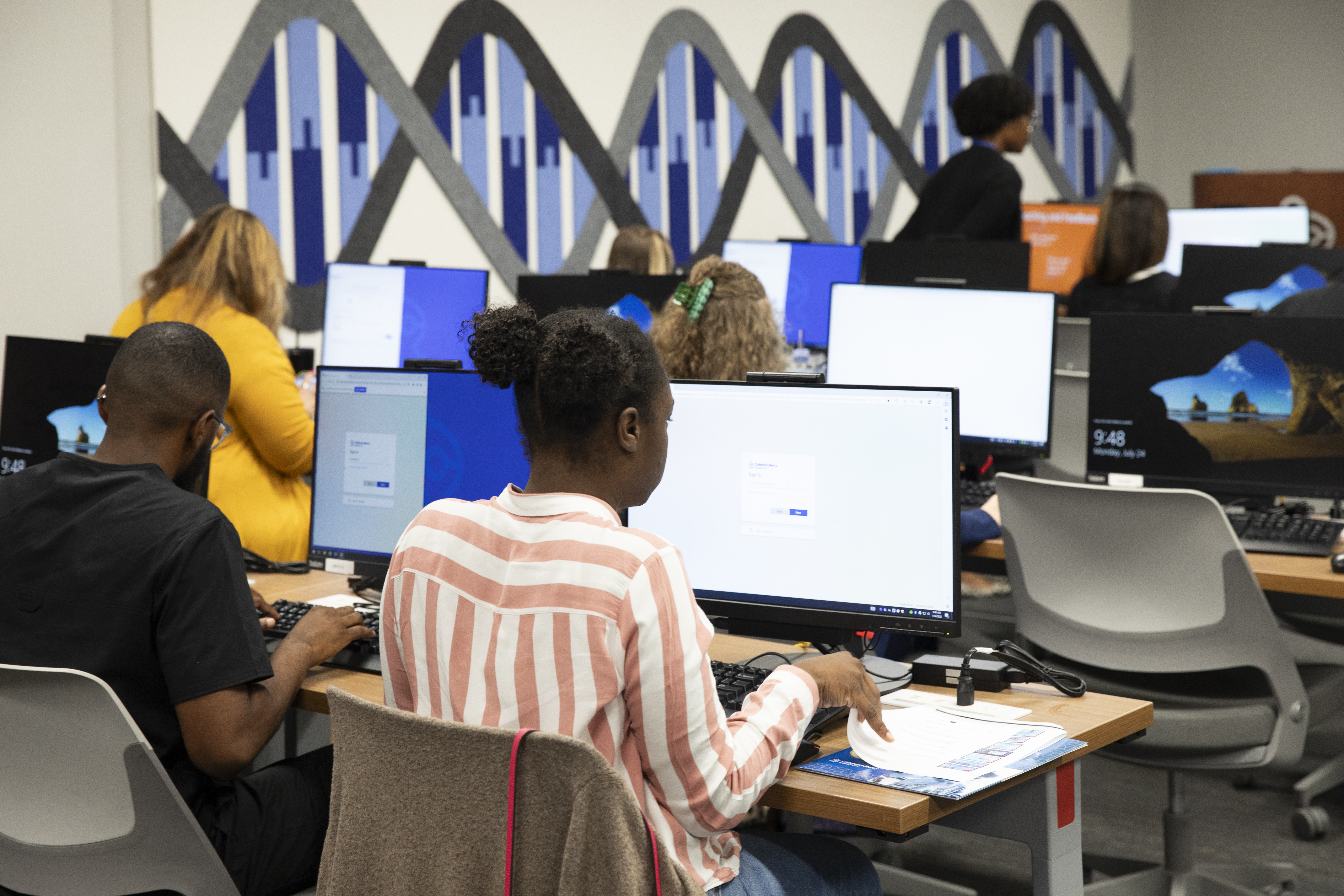 photo of several employees in a classroom style room working on computers