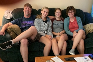 family of four smiling for the camera on the couch