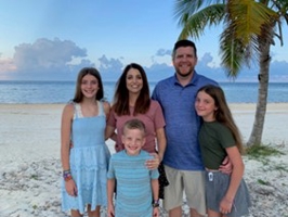 photo of family of five on the beach near a palm tree