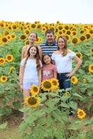 family of four posing for the camera in a field of sunflowers