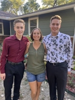 photo of three family members posing for a photo outside of a green house