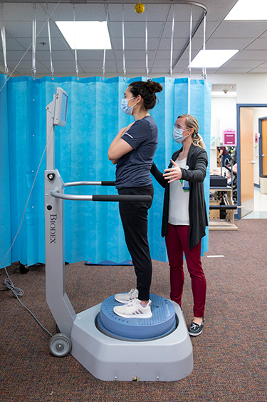 picture of patient stepping on machine and care team member standing on the floor to their side