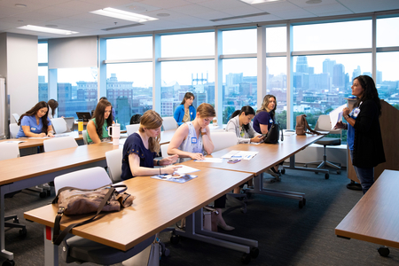 photo of employees sitting in a conference room that overlooks the city, a speaker is addressing the employees