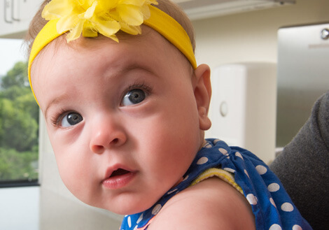 Infant wearing a yellow headband sitting in a pediatric clinic setting