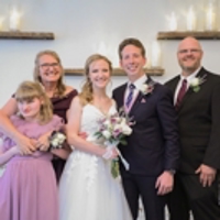 photo of family surrounding a bride and groom at a wedding at the alter