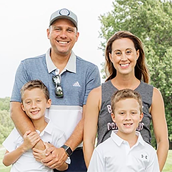 family of four posing for family picture outside