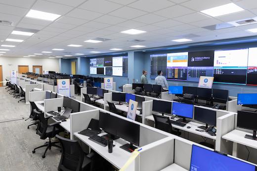 Technology operations center featuring multiple workstations and large display screens