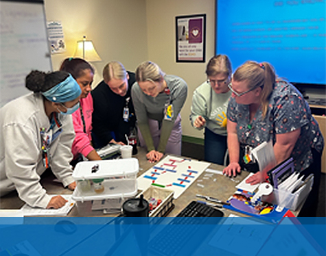 Six Children's Mercy Emergency Department staff standing around a table and looking at a paper with information.