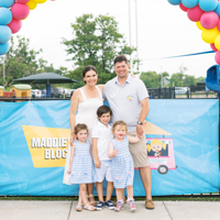 photo of family of five posing outside a community event with a balloon arch over them