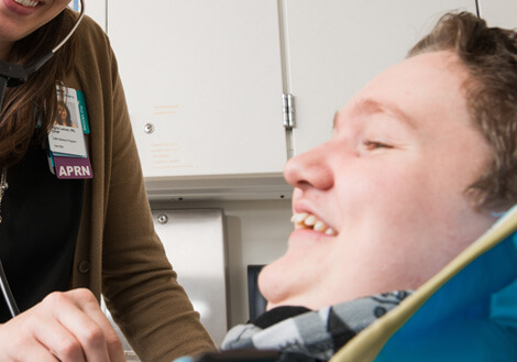 Health care team member listening to a patient's heartbeat with a stethoscope during a pediatric clinic visit.