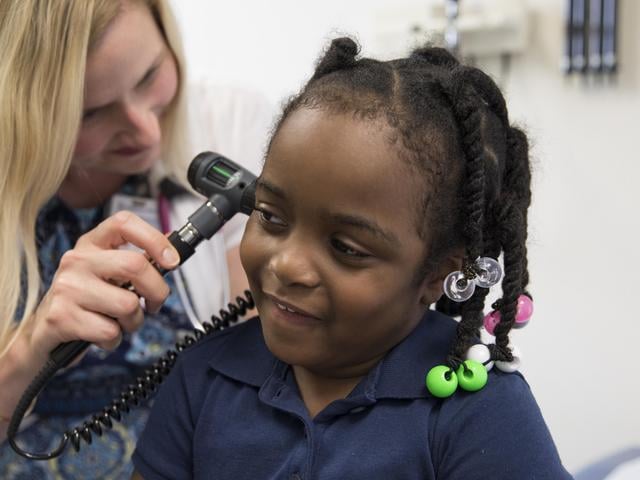 A clinician uses an otoscope to examine a child’s ear during a medical visit.