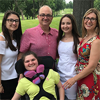 image of a family of five posing for a family portrait outside near a tree