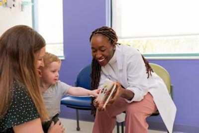 Health care provider showing a child and caregiver an educational tool or learning aid during a pediatric clinic visit.