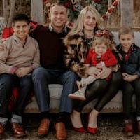 image of a family of 5 sitting on a couch posing for a family picture