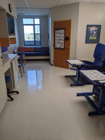 Private hospital patient room with a reclining treatment chair, visitor seating, work area and window.