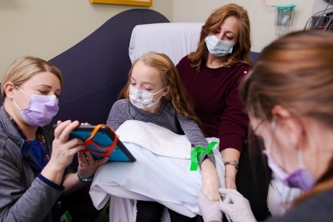 image of a nurse helping a child focus on entertainment while an IV is being placed