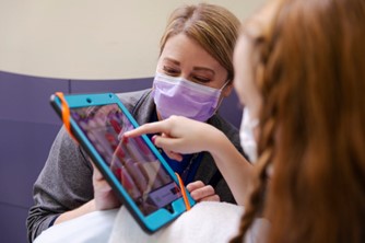 photo of a nurse working with a patient on a tablet