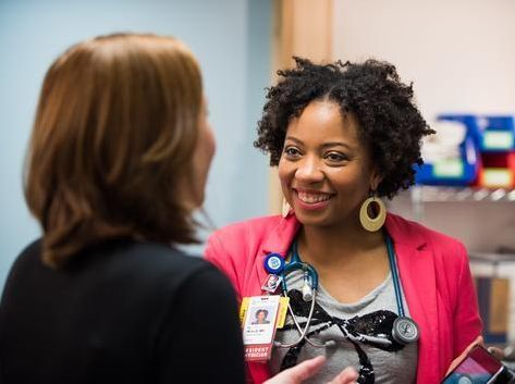 Health care professional speaking with another person in a clinical setting.