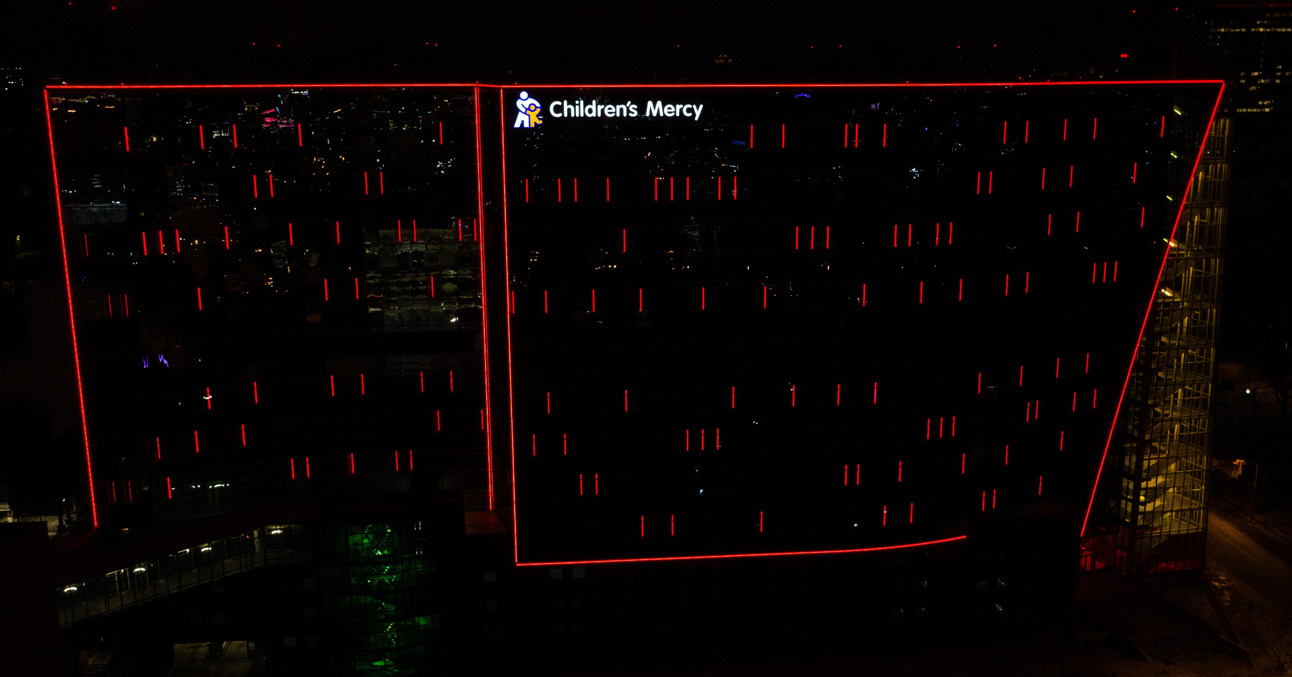 The outside of the CMRI building at night. The building is outlined in red with red lines on various windows.