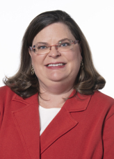 Brooke Fridley, PhD. Brooke has brown hair that falls to her shoulders and is wearing a red blazer.