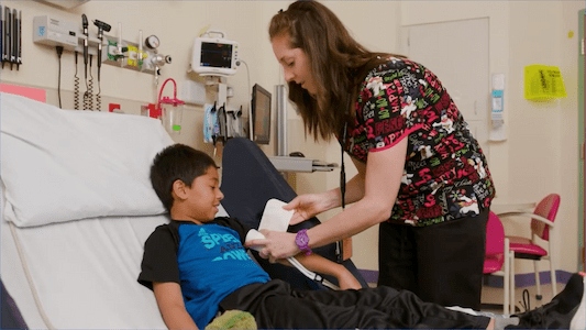 Health care team member caring for a child in a hospital bed during a visit