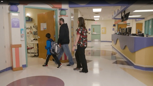 Child and caregivers walking through a Children's Mercy hospital unit toward a patient room