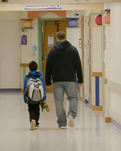Child and caregiver walking down a Children's Mercy hallway