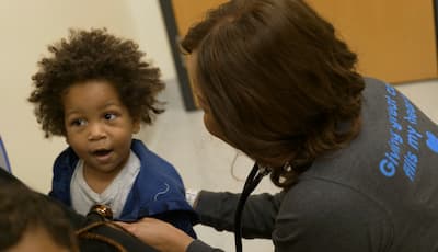 A female health care provider examines a young child with a stethoscope.
