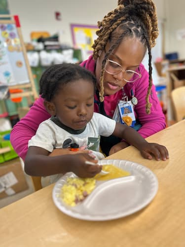 Child participating in a hands-on learning activity with support from an adult