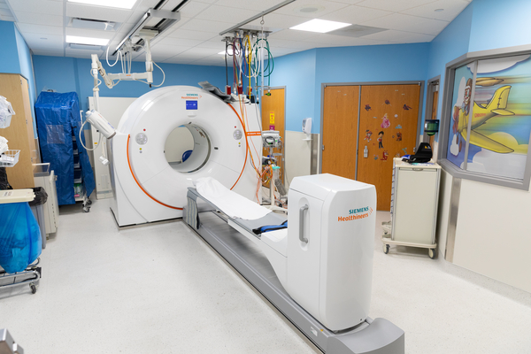 CT scanner in a pediatric imaging room, featuring a motorized scanning table, imaging equipment, colorful walls and child-friendly artwork