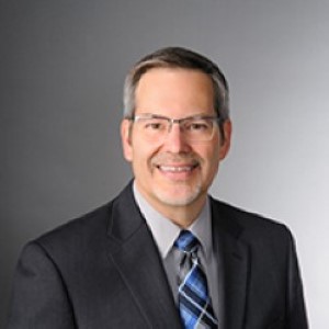 William Bednar - male in black suit with grey hair and glasses 