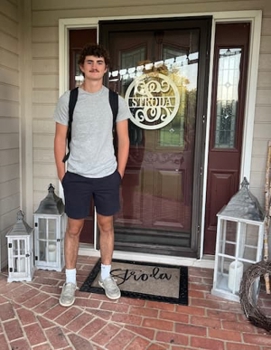 Young person wearing a backpack standing on the front porch of a home.