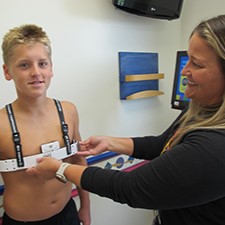 Child standing while a clinician adjusts a chest brace during a fitting appointment