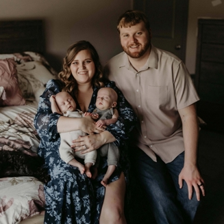 Two adults posing with two infants, with one adult holding both infants.