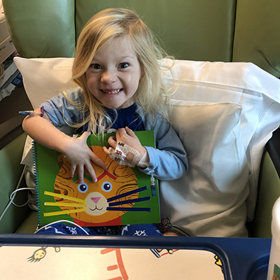  Young child sitting in a hospital chair holding a craft