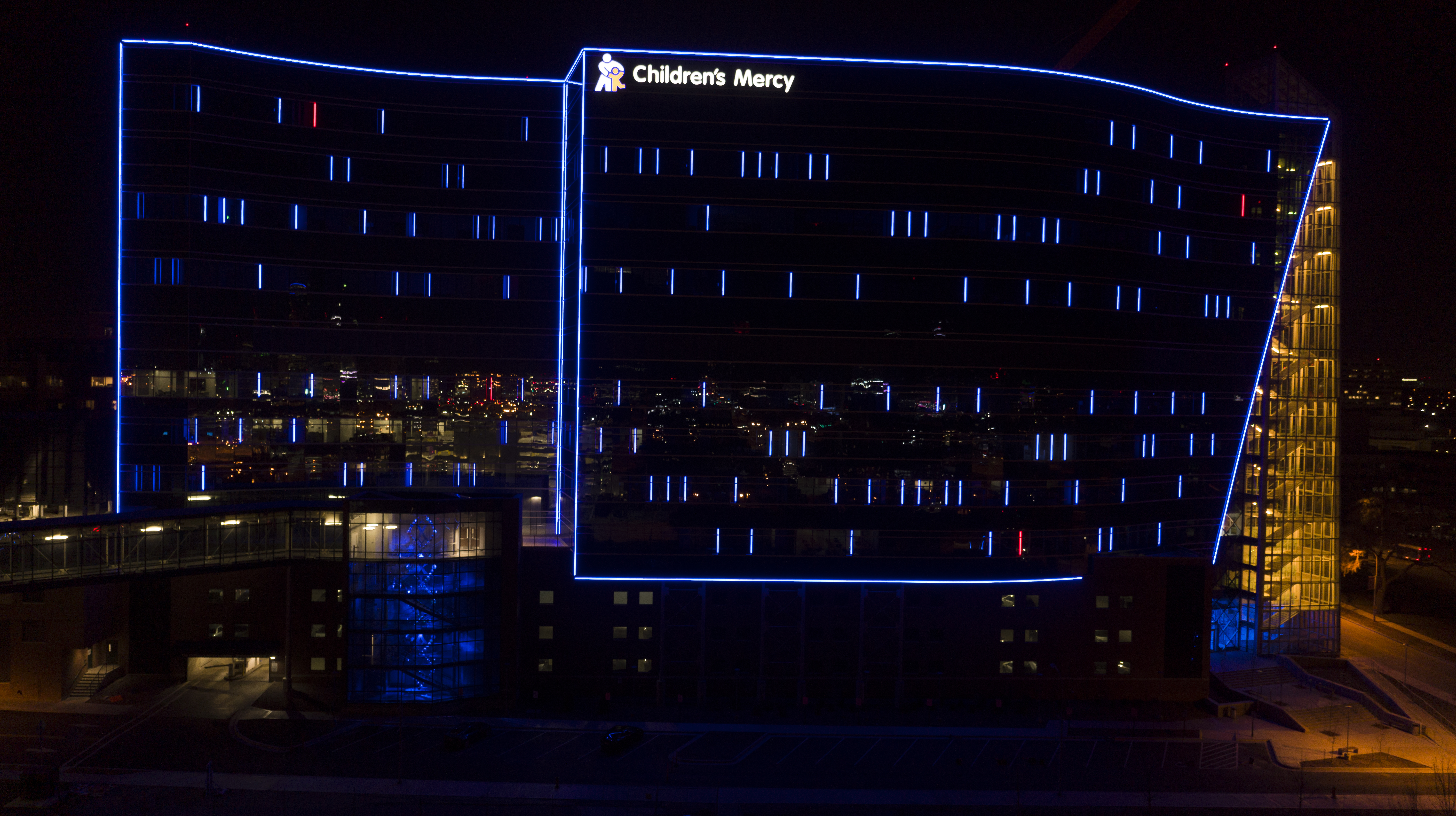 A photo of the outside of the CMRI building taken at night. The building is lit up in gold along the right staircase and blue outline over the rest.