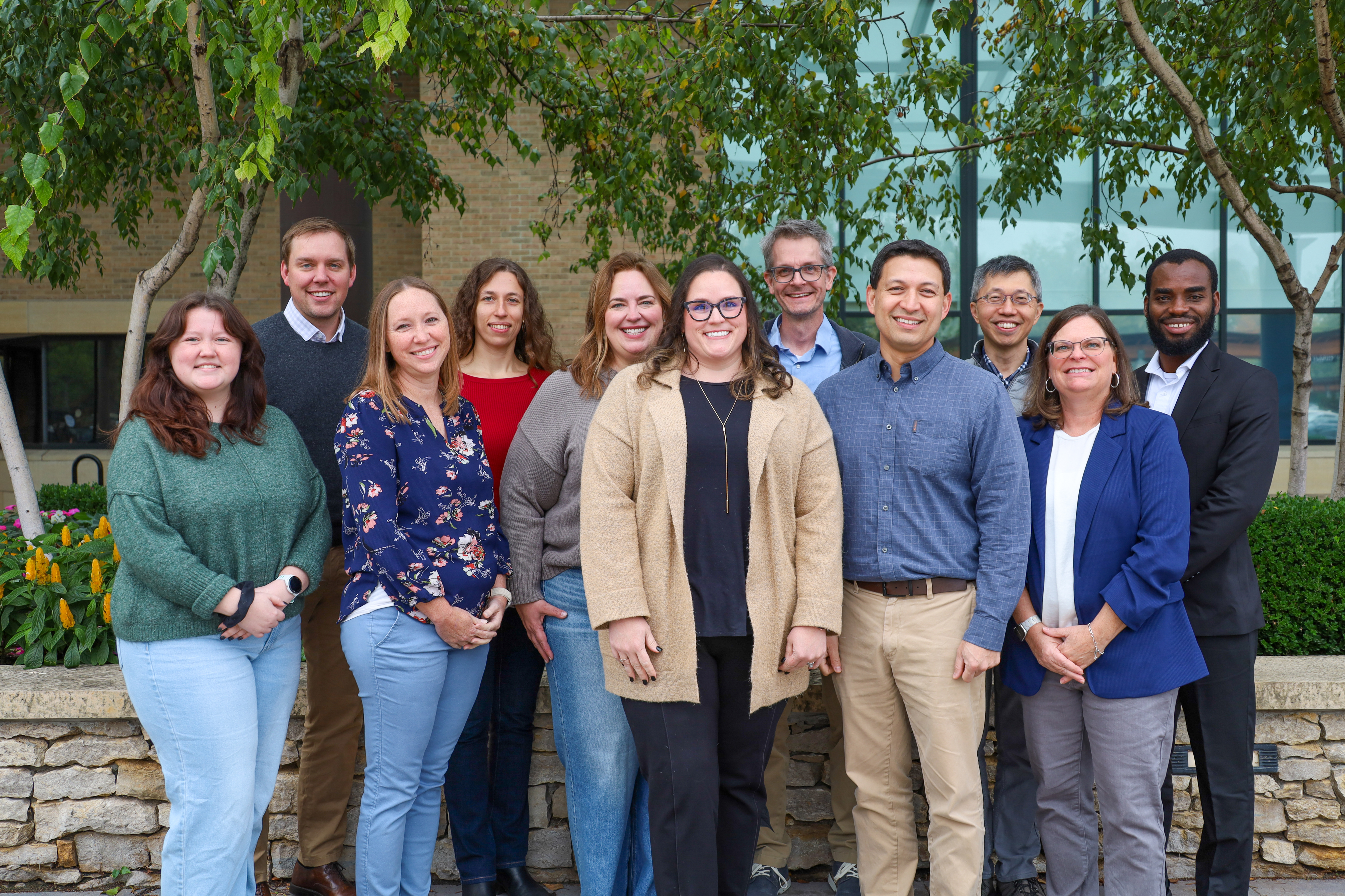 Members of the BCB team stand posing in two rows outside. 