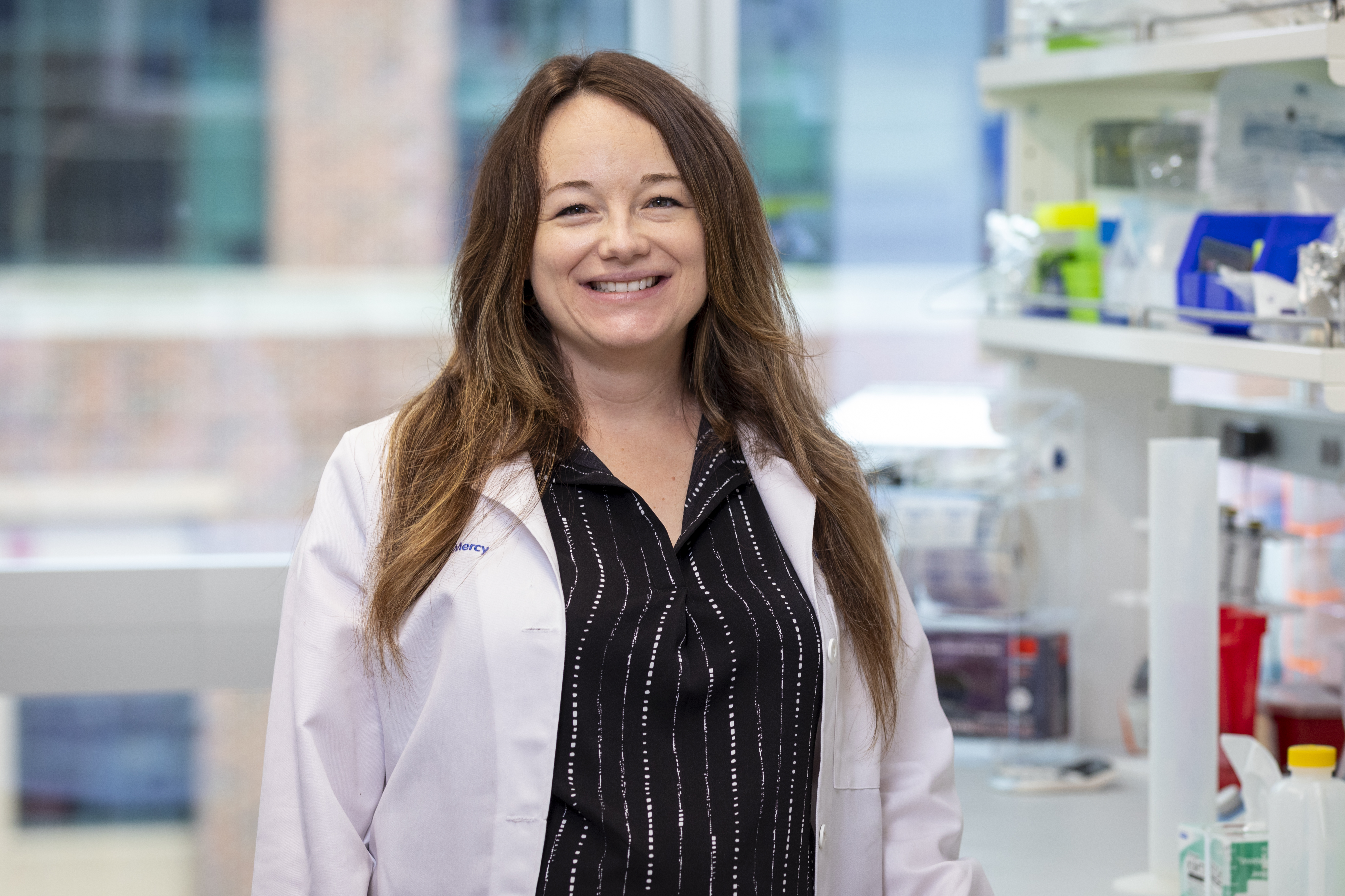 Dr. Alexandra Prosser-Dombrowski stands in a lab wearing a lab coat.