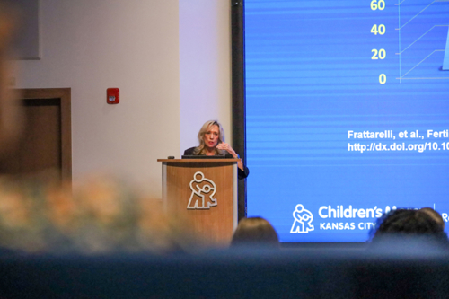 Dolores Lamb, PhD, HCLD (ABB), CC (NRCC) presents at a 2025 Research Month Lunch and Learn session. She stands at a lectern, motioning with her hand.