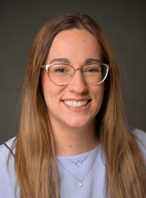 Abby Kietzman, vertical photo. She has long auburn hair and is wearing glasses.