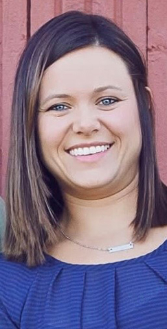 Ashley Parks. She has brown hair that falls to her shoulders and is wearing a blue shirt.